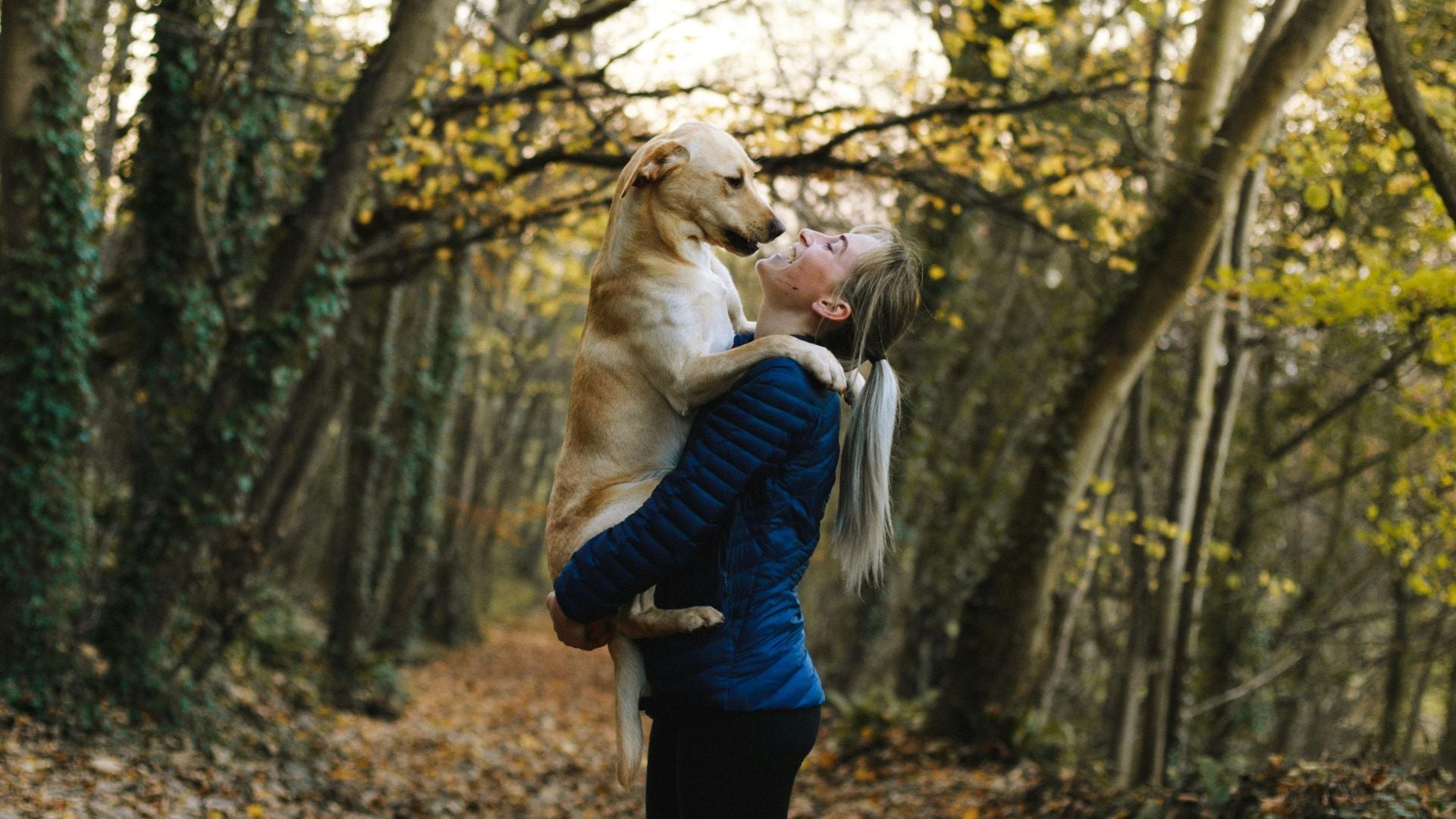 Woman holding her dog in her arms in the woods